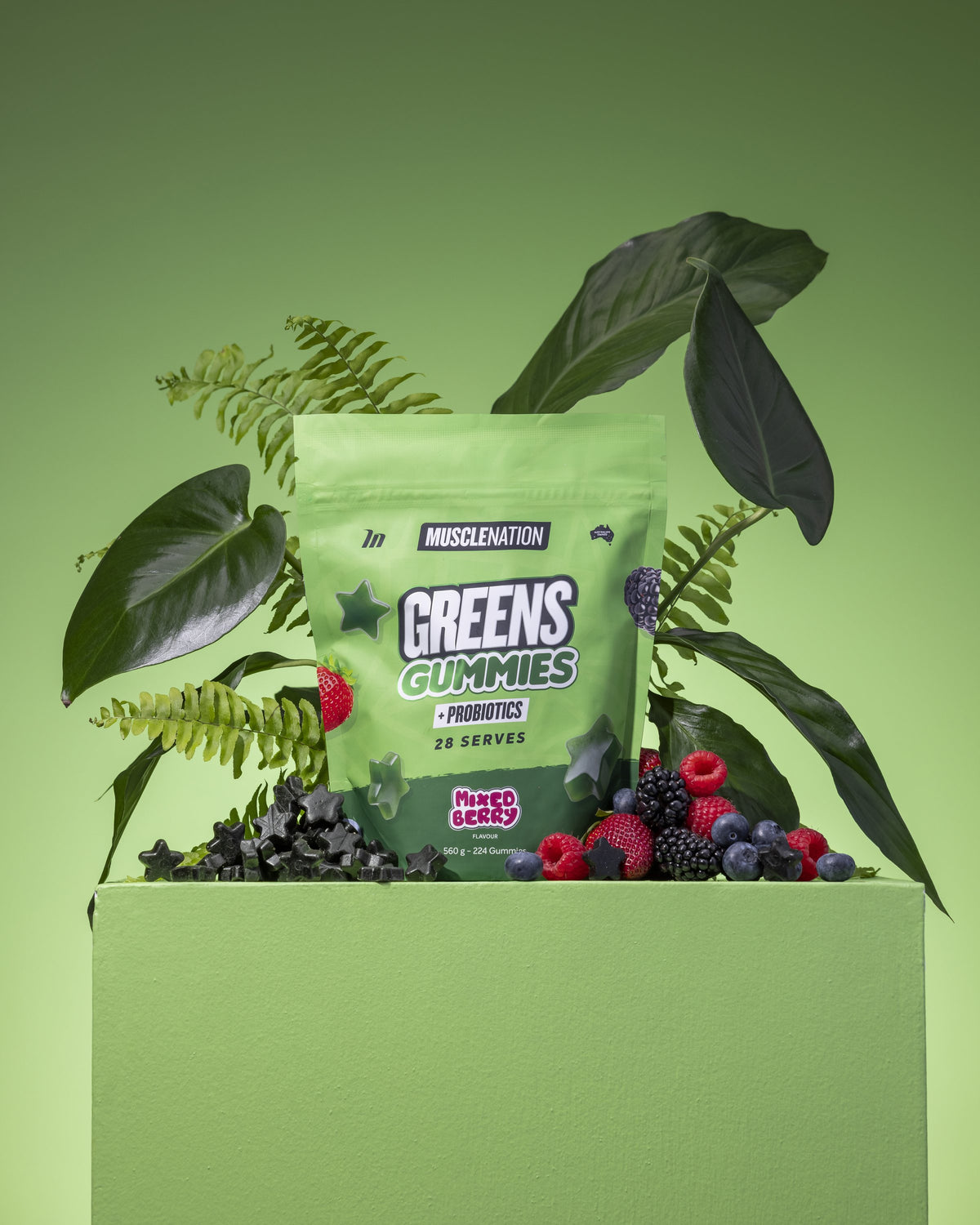Greens Gummies pouch on a green plinth with berries and leaves