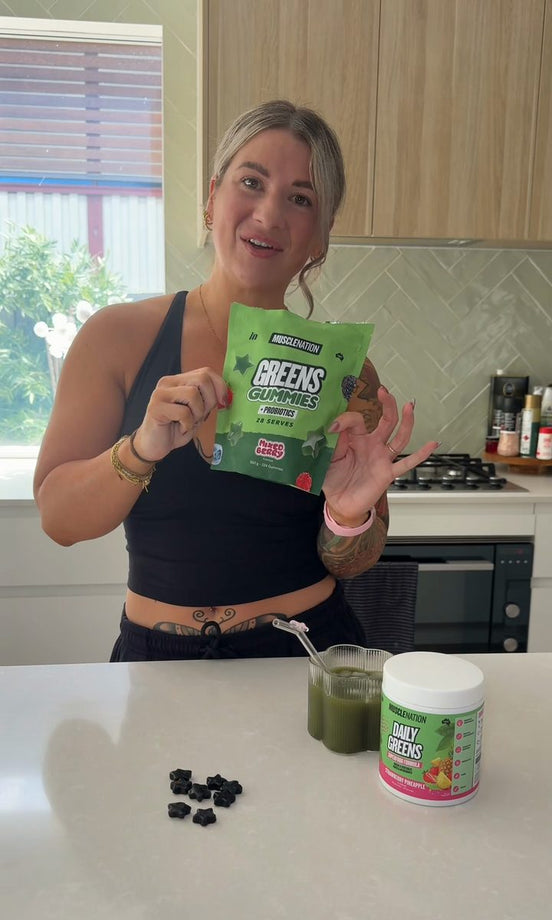 Ellie Wilson holding a pouch of Greens Gummies in her kitchen